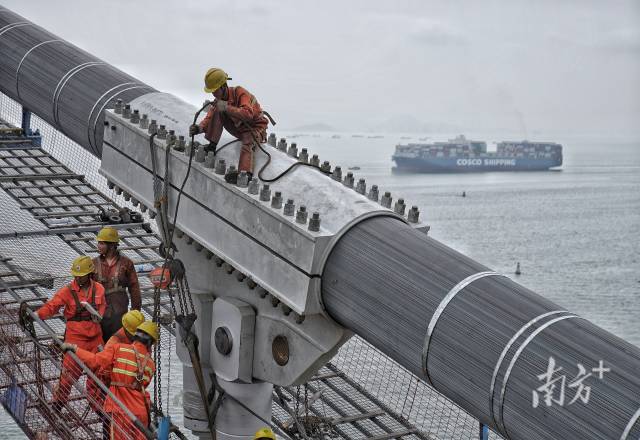 正在施工中的建設(shè)者身后，海上船舶往來(lái)不斷。  